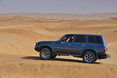 Keriya İlçesi, Çin-5 Ekim 2017: Turizm hizmetleri için gri-mavi SUV Taklamakan Çölü 'nün tehlikeli kumsallarında sürerken, bir yandan da off-road' un popüler bir biçimi olan kum tepeciklerini eziyor.
