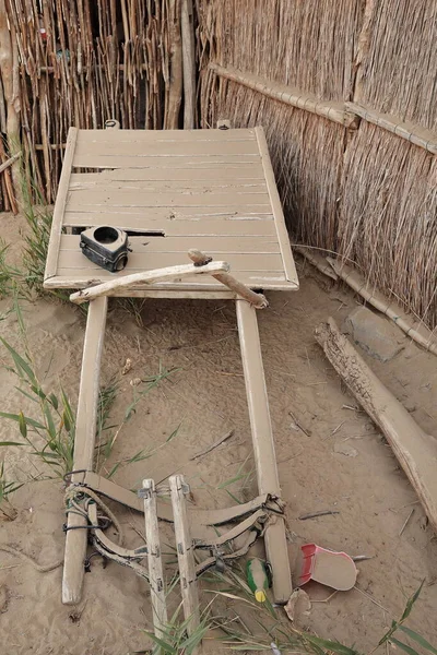 塔克拉玛干沙漠的维吾尔族人的旧木制手推车 满载着灰尘 被遗弃在前院的墙角芦苇和泥棚里 他们在那里养着几只巴氏骆驼 Keriya县 — 图库照片