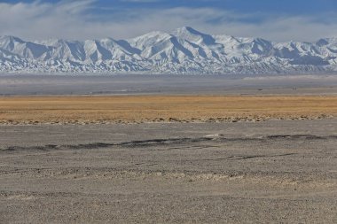 SW.wards view from Nnal.Highway G315 over the desert Qaidam basin to the snowcapped SE.end of the Eastern Qimantag range of the Kunlun mountains in the morning. Haixi prefecture-Qinghai province-China clipart