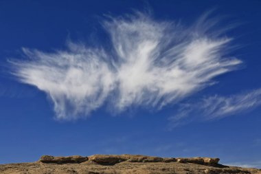 Curious trifid cirrus uncinus or mares.tails cloud over long yardang-eroded streamlined landform wind carved in tectonically folded sedimentary rock. 305 Prov.Road across Qaidam basin desert-Qinghai-China. clipart