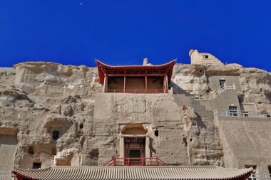 Two tiered-red painted wooden porch of cave 130 housing a 27 ms.high Buddha statue-Mogao Caves S.area of 492 caves and cell temples-Buddhist art from centuries 4th to 14th. Dunhuang-Gansu prov.-China. clipart