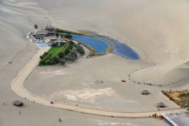 Şarkı söyleyen ya da Kum Dağı Mingsha Shan 'ın ortasındaki Hilal Gölü-Yueyaquan. Aslen Danghe nehrinin bir parçası olan vaha, Gobi Çölü 'nün doğal harikası olan rotasını değiştirdi. Dunhuang-Gansu-Çin