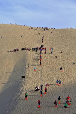 Dunhuang, Çin-13 Ekim 2017: Pazar günü boş zamanlarında insanlar, Gobi Çölü 'nün Kum Dağı-Mingsha Shan-Wonder' ı eşliğinde Hilal Gölü-Yueyaquan vahasının etrafındaki kumullarda kızakla kayıyorlar..