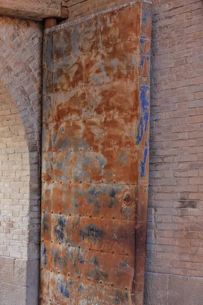 Rusty iron panel door leaf-spiked sheet metal-brick arched door of the Rouyuan Men-Conciliation Gate or West Gate giving way to the inner city. Jiayu Pass Fortress-Jiayuguan city-Gansu province-China.