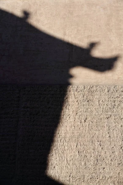 Game of light and shadow: silhouette of upturned upswept eaves-gable and hip roof of Gate Tower cast on the rammed soil wall of the inner fortress. Jiayu Guan Pass-Jiayuguan city-Gansu province-China.