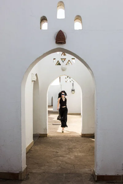 Attraktive junge Frau mit Sonnenbrille blickt in die Kamera, während sie an einem weißen Gebäude in Ägypten spaziert — Stockfoto