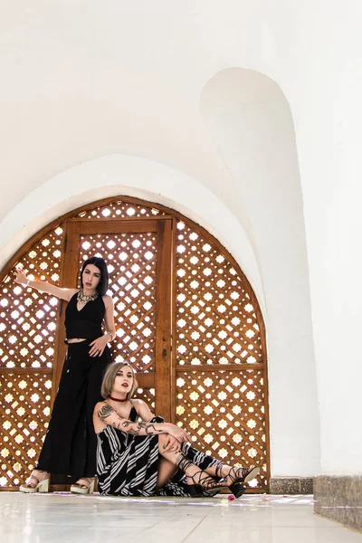Belle ragazze alla moda guardando la fotocamera e posa vicino a cancelli di legno decorativi in Egitto — Foto stock