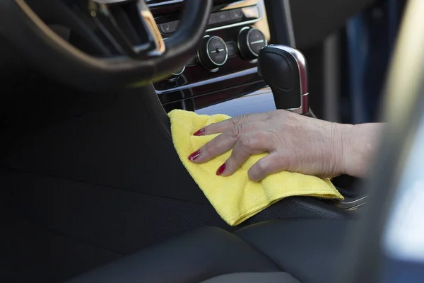 Mature woman hand with microfiber cloth cleaning vehicle interior panel. Car wash and maintenance commercial.
