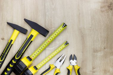 Ahşap arka planda ahşap işçiliği ve ev aletleri. Çekiç, kerpeten, tel kesici ve çelik mezura.