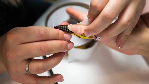 Tırnak cilasının ustası güzellik salonundaki ojeleri yapmadan önce parmağına sabitleyici sürüyor. Eller için profesyonel bakım