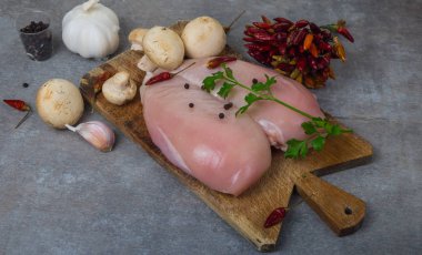 Çiğ tavuk göğsü ve baharatlar ahşap kesim tahtasının üzerinde, yakın görüş.