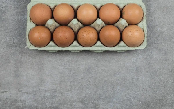 Plastic tray with chicken eggs on a gray concrete background. Top View.