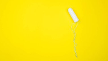 Parlak sarı arka planda beyaz pamuklu tampon. Adet döngüsü renkli düz yatıyordu. Kritik günler ve adet dönemi konsepti. Kadın hijyeni. Kadın regli. Stok fotoğrafı