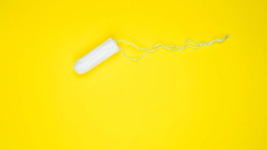 Kadınlar için hijyenik beyaz tampon. Pamuklu çubuk. Regl, korunma aracı. Sarı arkaplanda tamponlar