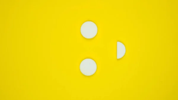 Pastillas blancas sobre un fondo de gradiente amarillo con espacio para copiar en forma de sonrisa. El concepto de farmacología, vitaminas y píldoras para niños. Emociones positivas. foto vertical — Foto de Stock