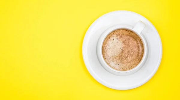 Sarı arkaplandaki kahve fincanının üst görüntüsü. Düz yatıyordu. Boşluğu kopyala