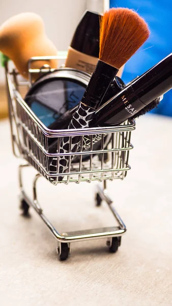 Winkelwagen met cosmetica, kralen, haar clip op de oude houten achtergrond. Getinte afbeelding — Stockfoto