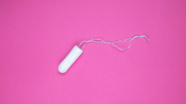 Pembe arka planda tıbbi kadın tamponu. Kadınlar için hijyenik beyaz tampon. Pamuklu çubuk. Regl, korunma aracı. Kırmızı arkaplanda tamponlar