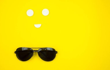 Siyah telefon, sarı arka planda güneş gözlüğü. Üst Manzara. Boşluğu kopyala