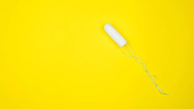 Ayellow arka planında tıbbi kadın tamponu. Kadınlar için hijyenik beyaz tampon. Pamuklu çubuk. Regl, korunma aracı. Kırmızı arkaplanda tamponlar