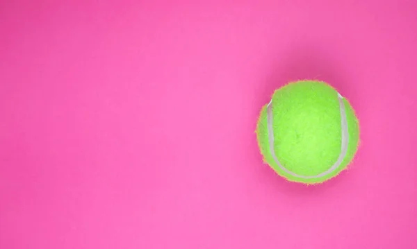Зелений тенісний м'яч на рожевому фоні. вид зверху. копіювання простору. Афіша — стокове фото