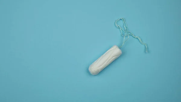 Tampón médico femenino sobre fondo azul. Tampón blanco higiénico para mujeres. Un hisopo de algodón. Menstruación, medios de protección. Tampones sobre fondo rojo —  Fotos de Stock