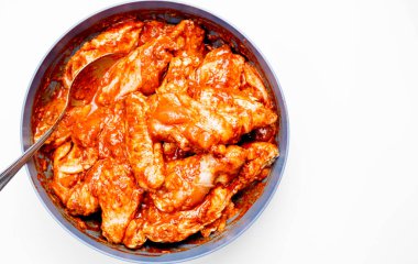 Terbiye edilmiş tavuk kanatları, beyaz arka planda bir tabakta.