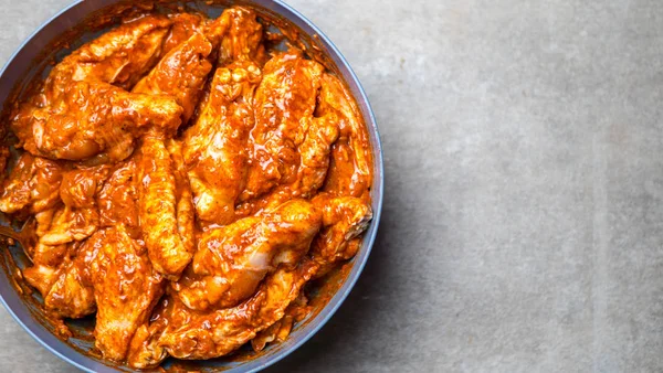 Marinated chicken wings in a plate on a gray background