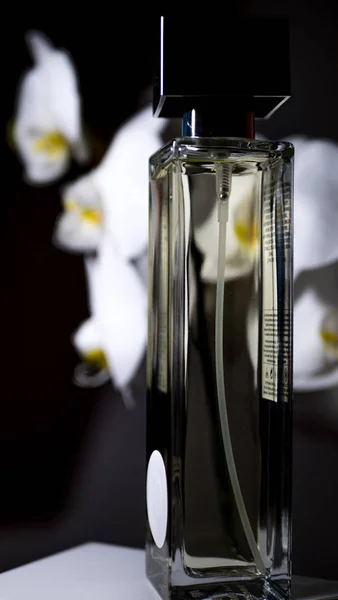 Frasco de perfume con flores de orquídea sobre fondo negro. copiar espacio, texto, diseño, banner. concepto de belleza — Foto de Stock