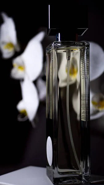 Botella con perfume sobre fondo de flores de orquídea — Foto de Stock