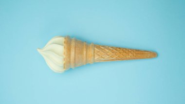 Vanilyalı dondurma koni mavi soluk pastel renk arka plan üzerinde. Vanilyalı gofret Kupası