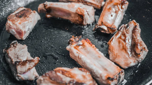Обсмажування сковороди зі смаженими свинячими ребрами на темному дерев'яному фоні, студійний знімок — стокове фото