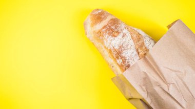 Italian bread in paper ball on yellow background. Top view