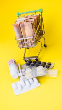 shopping cart full of medicine with pills and capsules and euro banknotes. money . drug cost concept