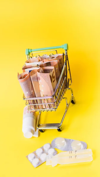 Shopping cart full of medicine with pills and capsules and euro banknotes. money . drug cost concept — Stockfoto