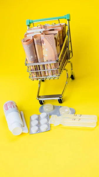 タブレット、ショッピングカート、ユーロ紙幣、医薬品、健康保険、医療費の象徴的な写真。高価な治療法の概念 — ストック写真