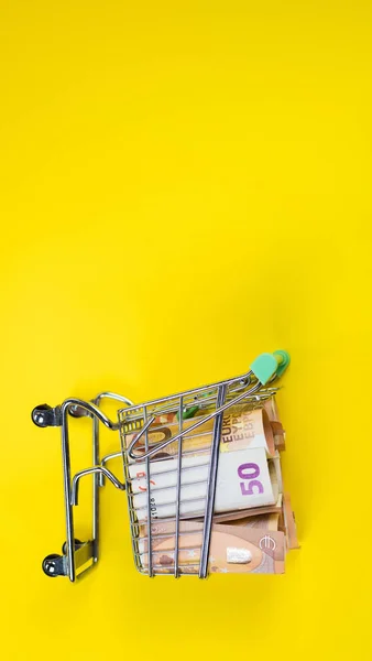 Порожній кошик на банкнотах євро, на жовтому тлі. Концепція продовольчого кошика або купівельної спроможності — стокове фото
