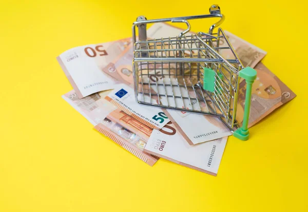 empty empty basket on euro banknotes, on yellow background. Concept of food basket or purchasing power