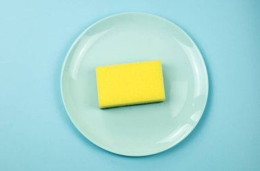 Sarı temizleme süngeri mavi arka planda yeşil plaka ve kopyalama alanı