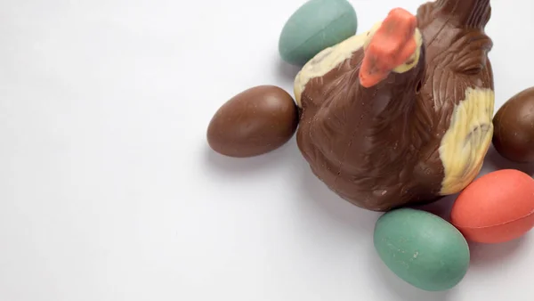 Galinha de chocolate de Páscoa e ovos coloridos, em um fundo branco, vista superior — Fotografia de Stock