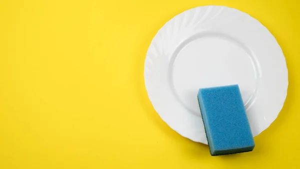 带复制空间的黄底白盘上的蓝色清洁海绵 — 图库照片