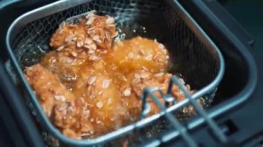 Kızarmış tavuk pişiriyorum. Kızarmış tavuk nuggetlarını kızgın yağda kızartma makinesine yakın.