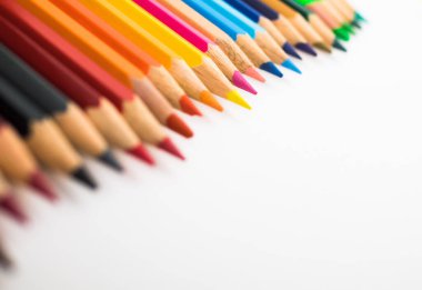 Beyaz arkaplanda bir sürü farklı renkli kalem var. Uzayı kopyala seçici odak.