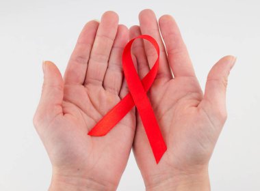 Sağlık ve tıp konsepti - kırmızı AIDS farkındalığı kurdelesi tutan kadın elleri.