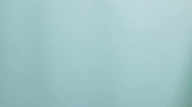 Kadın eli, mavi arka planda baş parmağını gösteriyor.