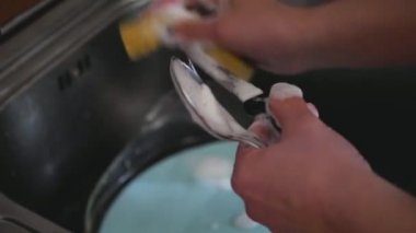 Kadın elleri mutfak lavabosunda bulaşık yıkıyor. Ev işlerini yapıyor. Tabak yıkama rutini, ağır çekim, statik kamera.