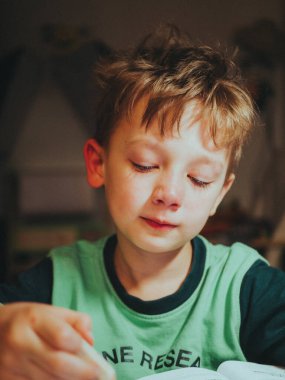 Çocuk ders yazıyor, uzaklardan öğreniyor. Ders yazmaya isteksiz..