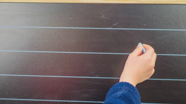 Little schoolboy writing on blackboard at home.