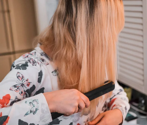 Szőke Fürdőszobában Kiegyenesíti Haját Egy Hajsütővassal — Stock Fotó