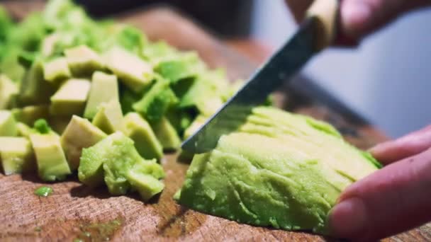 Mão feminina com faca de cozinha cortando abacate em pedaços para salada. Conceito de alimentação saudável. Processo de culinária, estilo de vida vegetariano, estar em uma dieta. Vista de perto de cortar frutas de abacate — Vídeo de Stock